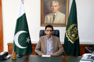 dr khalid maqbool siddiqui sitting on a chair with 2 flags left right